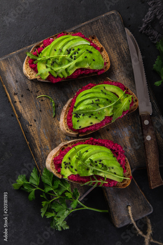 toasts with beetroot hummus and avocado on cutting board