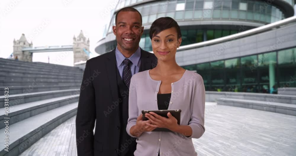 Confident male and female black business partners posing outside their place of work together, Young aspiring African business professionals standing happily outside in London, 4k Confident male and female black business partners posing outside their place of work together, Young aspiring African business professionals standing happily outside in London, 4k