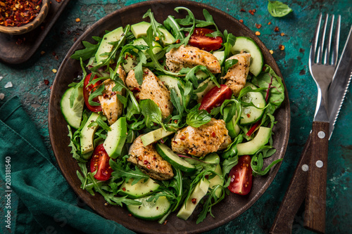 roasted chicken, avocado, tomato, cucumber and arugula salad, top view, green background