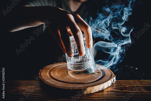 Obraz na plátne Barman prepares cocktail with smoke, raises a glass, pours alcohol