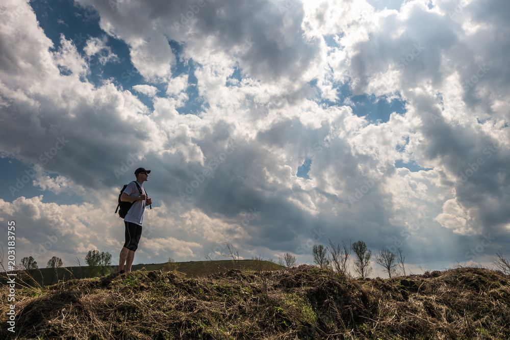 young man with a backpack stands on top in the mountains against the background of a beautiful sky with storm clouds. Sense of freedom young man with a backpack stands on top in the mountains against the background of a beautiful sky with storm clouds. Sense of freedom