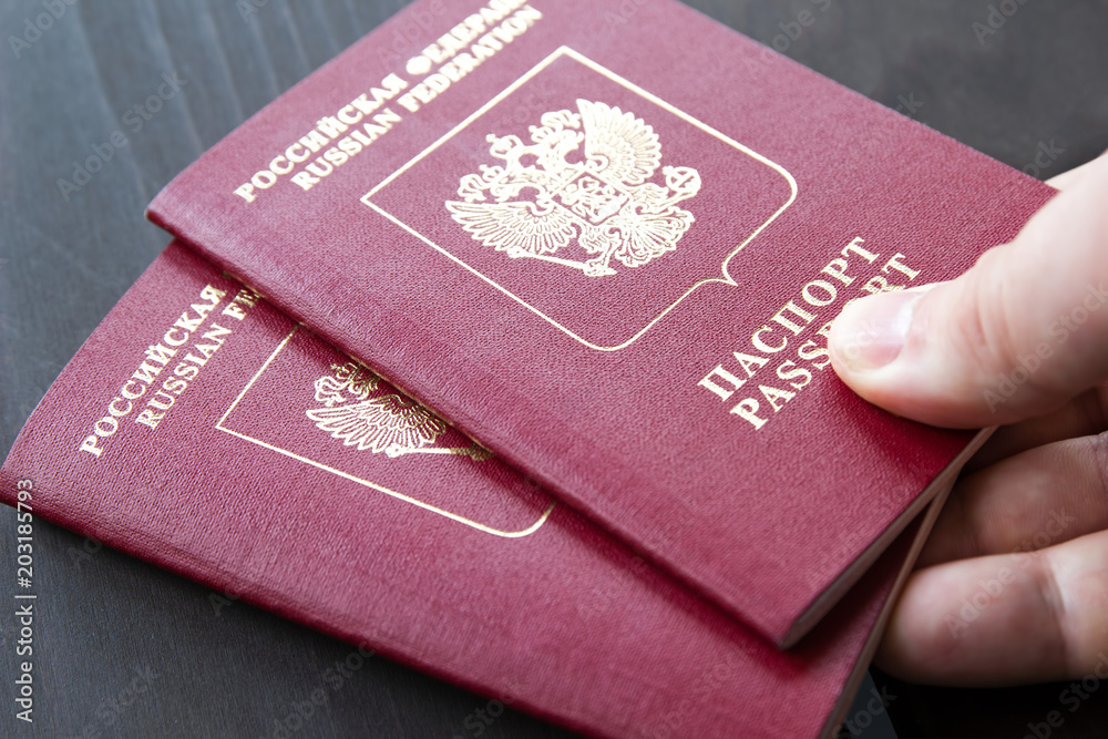 Two russian passports in hand. Russian official document on wooden background Two russian passports in hand. Russian official document on wooden background