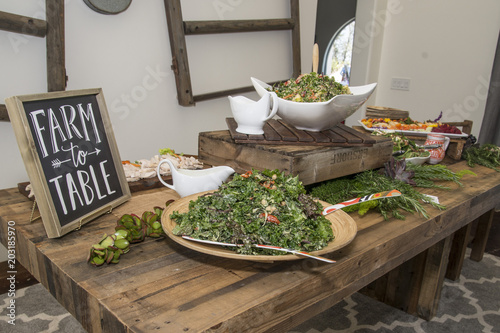 A salad of leafy greens looks appetizing, nutritious and delicious on a wooden table with dressing on the side.