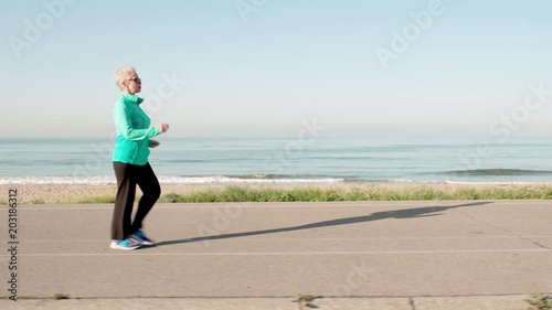 71 year old woman gets her exercise by walking along the beach. photo
