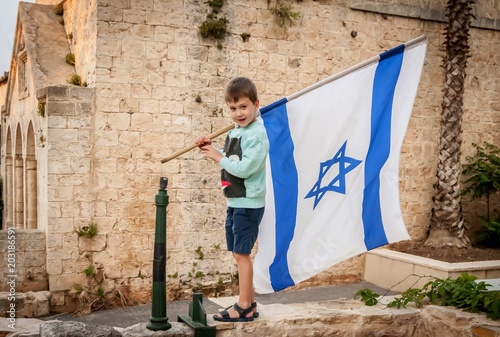 Fényképezés Cute Caucasian boy with a large flag of Israel in his hands.