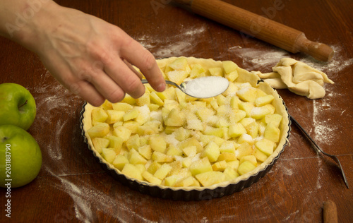 A woman's hand spits sugar. prepare apple pies