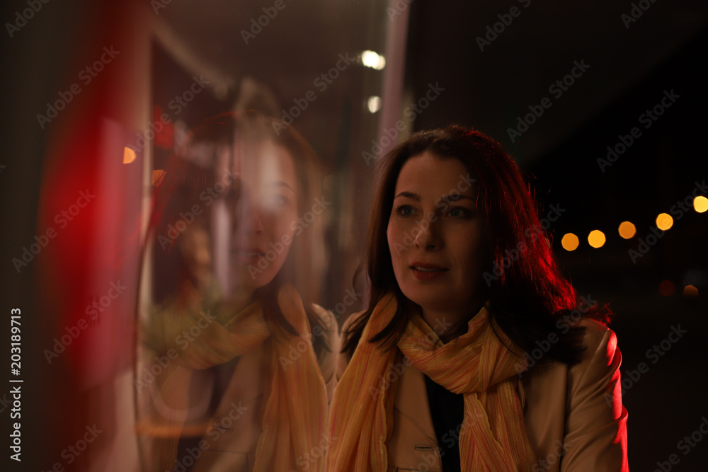 Girl brunette near in the shopwindow on the night city street