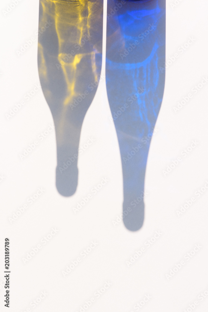close up view of colorful bottles shadows on white surface close up view of colorful bottles shadows on white surface