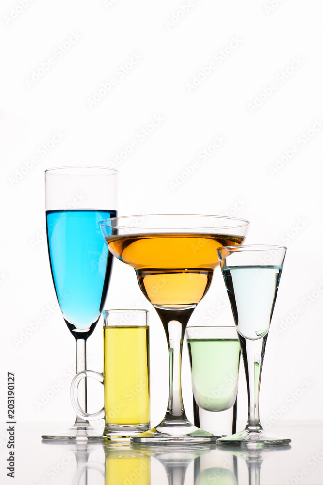 close up view of various alcohol cocktails in glasses on white backdrop