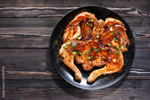 Grilled fried roast Chicken Tabaka on a plate on a wooden background, top view