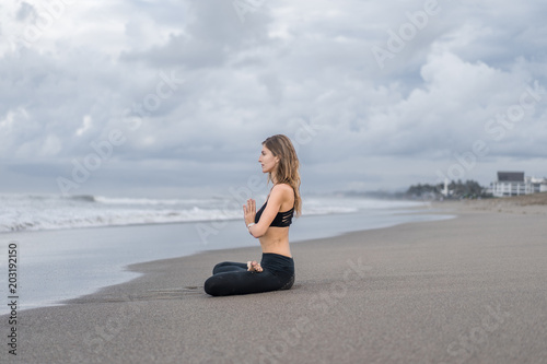 side view of beautiful young woman practicing yoga in lotus pose (padmasana) with namaste mudra on seashore © LIGHTFIELD STUDIOS