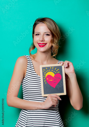 Young girl holding a board with demonstration of good health of heart on green background