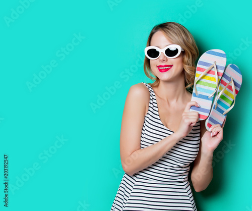 Young woman with flip flops shoes on green background