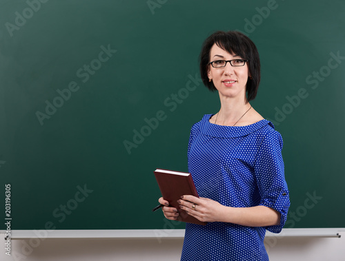 woman teacher posing by chalk Board, learning concept, green background, Studio shot