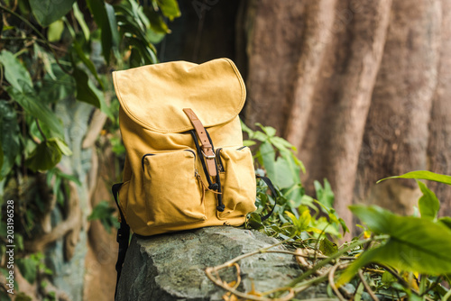 Fototapeta Naklejka Na Ścianę i Meble -  close-up shot of vintage yellow backpack on rock in jungle