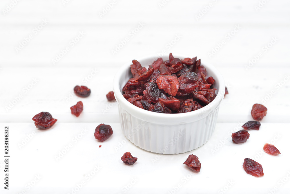 Dried cranberries in a bowl on white wooden background Dried cranberries in a bowl on white wooden background