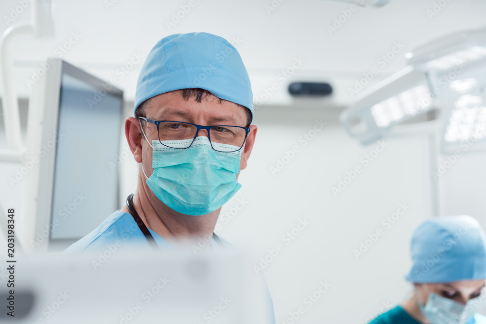 Anesthetist watching patient sleeping in operation room monitoring vital functions Anesthetist watching patient sleeping in operation room monitoring vital functions