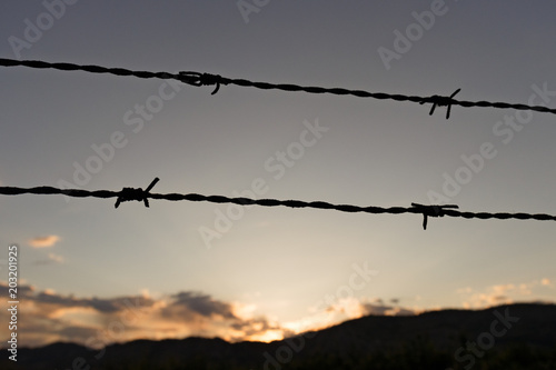 barbed wire fence in front of sunset