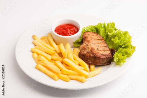 beautiful photo close-up menu of fresh tasty French fries and meat and salad on a plate on a white background
