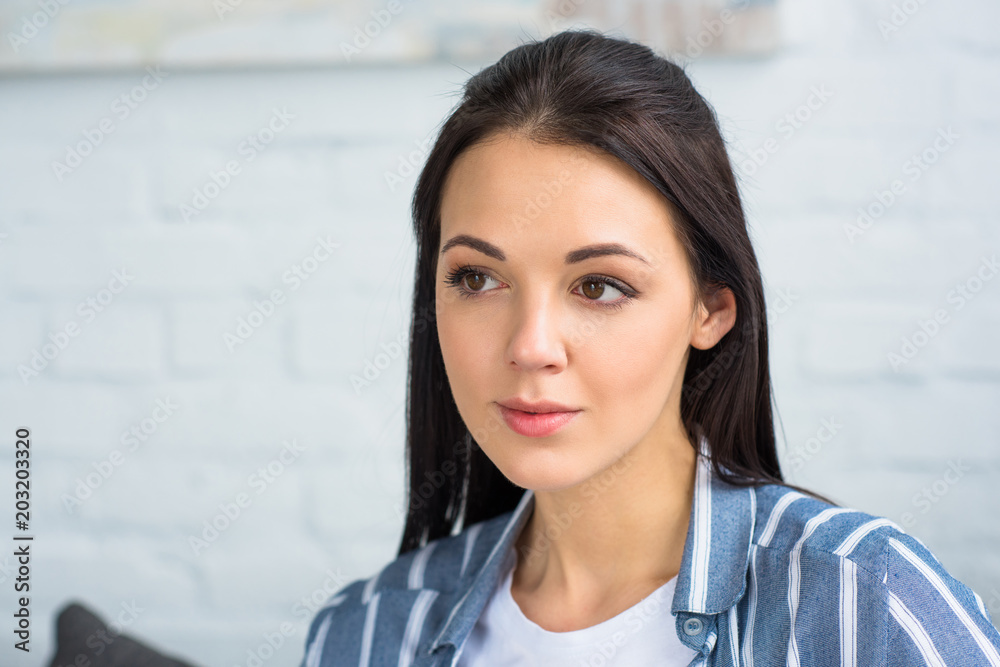 portrait of young pensive woman looking away at home
