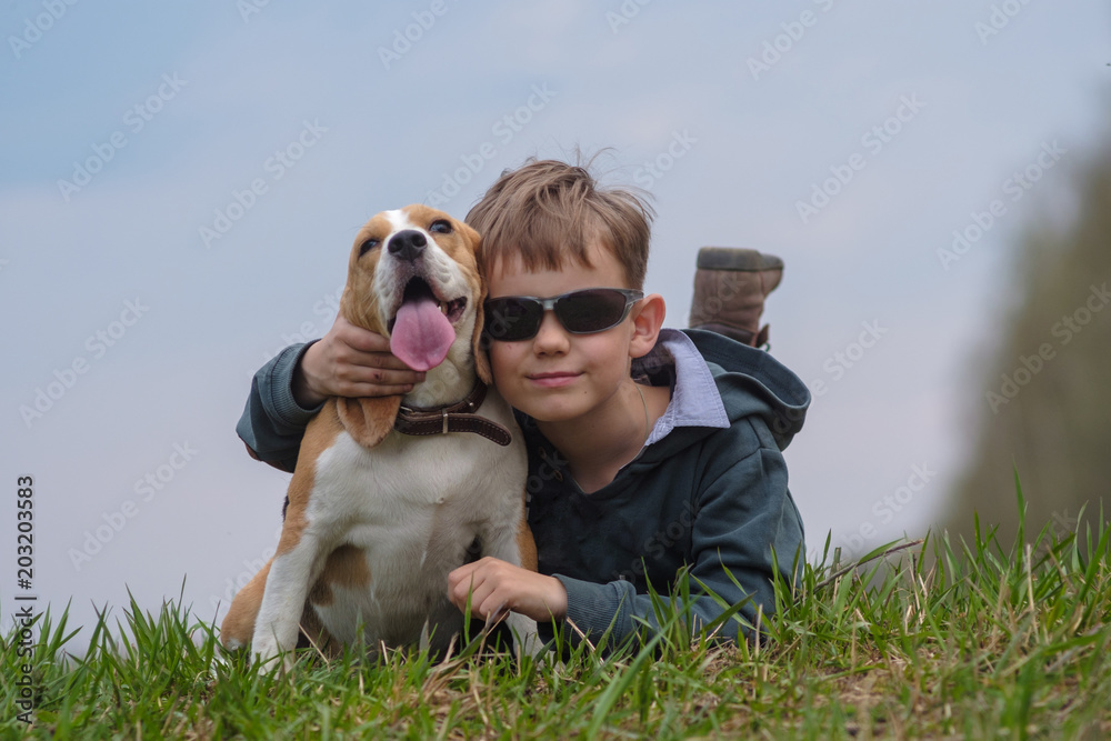 European boy with Beagle dog lying on grass