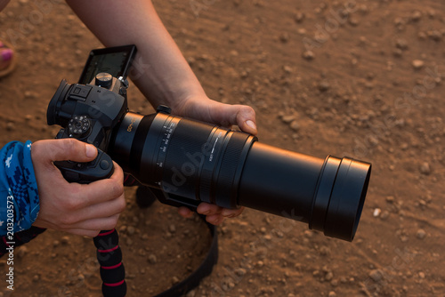 Film maker preparing dslr camera with big lens to filming in glory of afternoon light. 