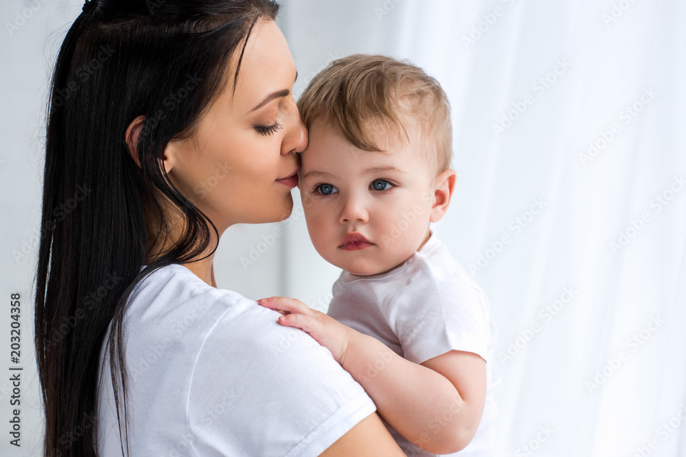 smiling tender mother holding cute baby boy in hands at home smiling tender mother holding cute baby boy in hands at home