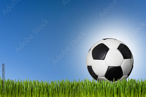 Fußball auf Wiese vor blauem Himmel
