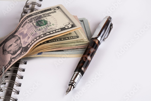 Dollar banknotes and pen, notebook