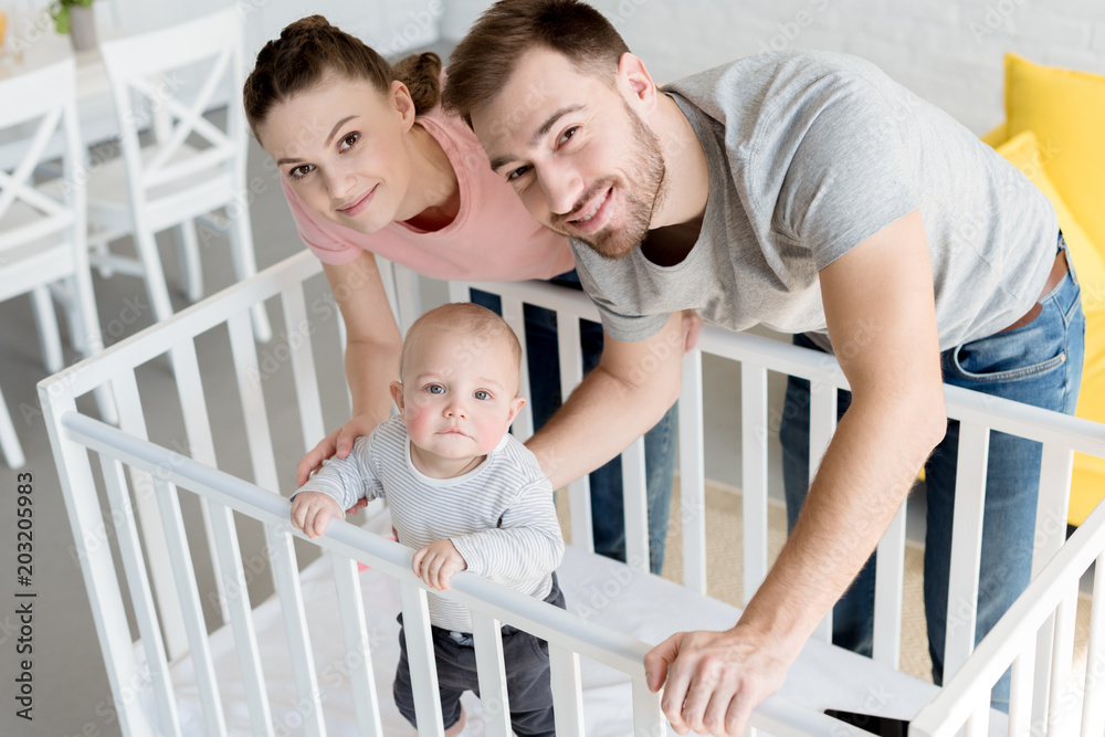 Obraz premium happy parents with little son in baby crib at home