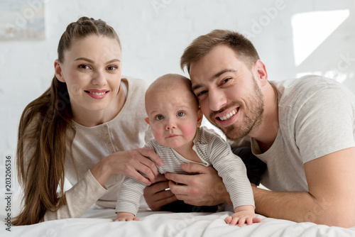 smiling parents with little boy on bed