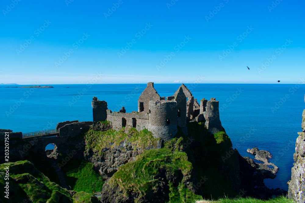 old medieval Dunluce castle against blue ocean water and sky during sunny day 