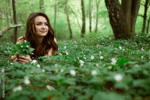 The girl keeps flowers and lies on the ground