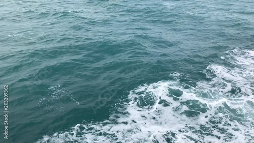 Sea water waves on side of boat while moving, Boat cutting water surface during cruise. Water splashing on blue ocean.