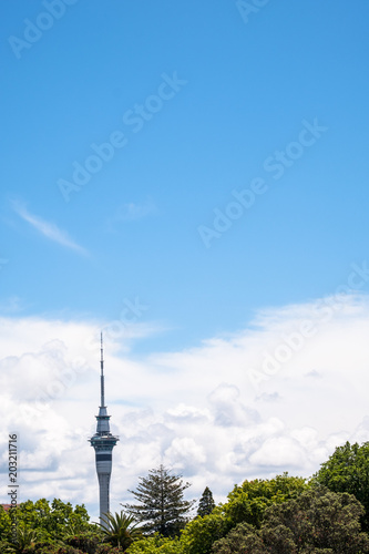 Auckland Skytower over the green trees with clouds and blue sky.