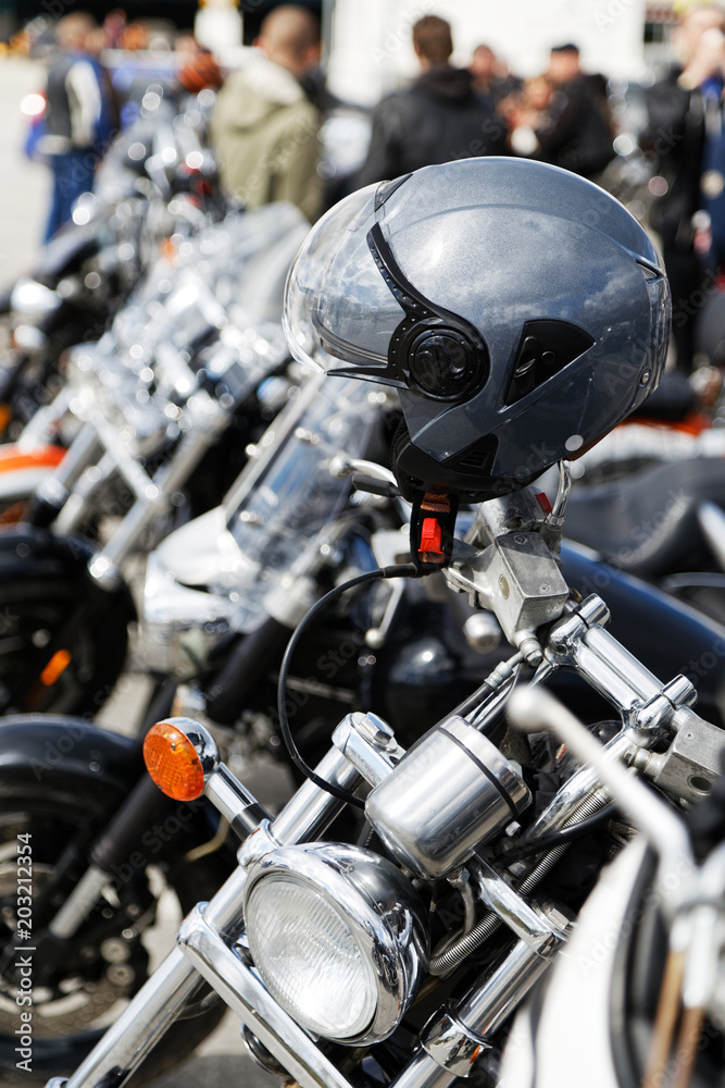 Fototapeta premium Grey moto helmet on motorcycle handlebars against blurred background