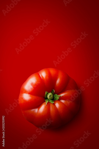 Tomato on a red background viewed from above. Fresh vegetable food. Copy space. Top view