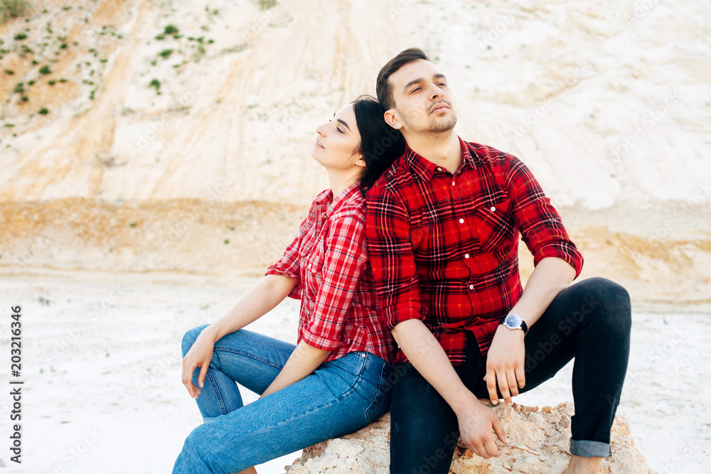 Beautiful couple sits and relaxs on a stone in a canyon. Romanticism. Travel concept. Copy space Beautiful couple sits and relaxs on a stone in a canyon. Romanticism. Travel concept. Copy space