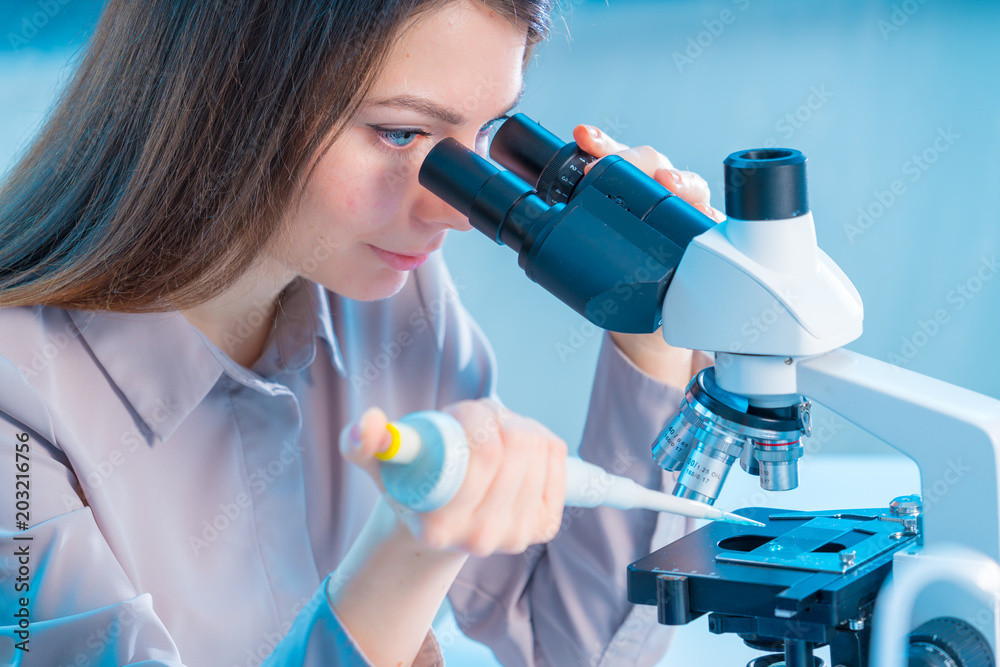 Young chemist in the laboratory. Scientist Using Microscope In Lab