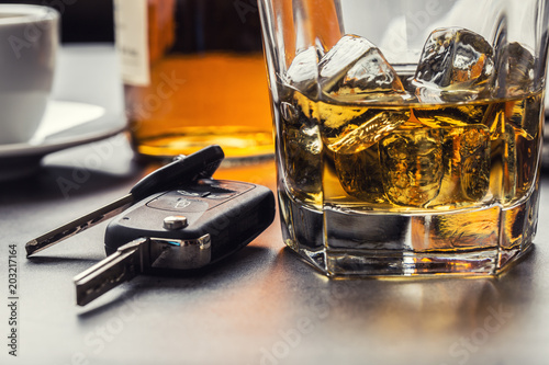 Car keys and glass of alcohol on table. photo