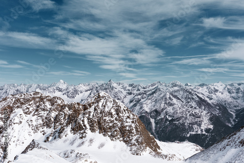 Alpine panoramic Alpine landscape. Mountain peaks in the snow on a background cloudy sky © Bakulov