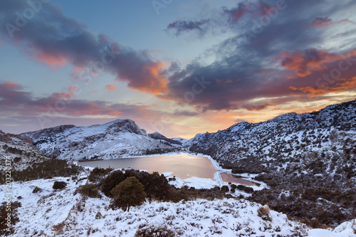 Snow in Majorca. Snowy landscape with lake and mountains at sunset time. Serra de Tramuntana range.