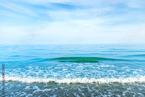 Blue sea water with waves, foam and white clouds on the sky. Calm tropical landscape © Pavlo Vakhrushev