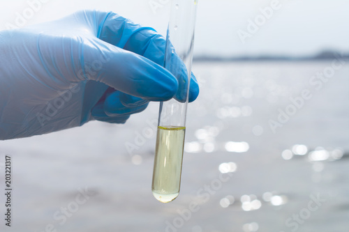 Hand in glove collects water in a test tube. Concept - water purity analysis, ecology. Water testing for infections