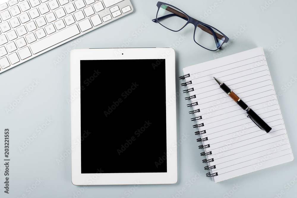 Tablet and notebook next to pen and glasses. Workplace. Technology.