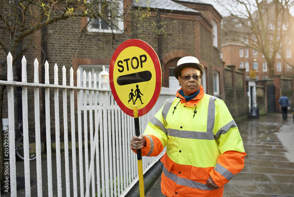 Portrait of crossing guard holding stop sign Photos | Adobe Stock