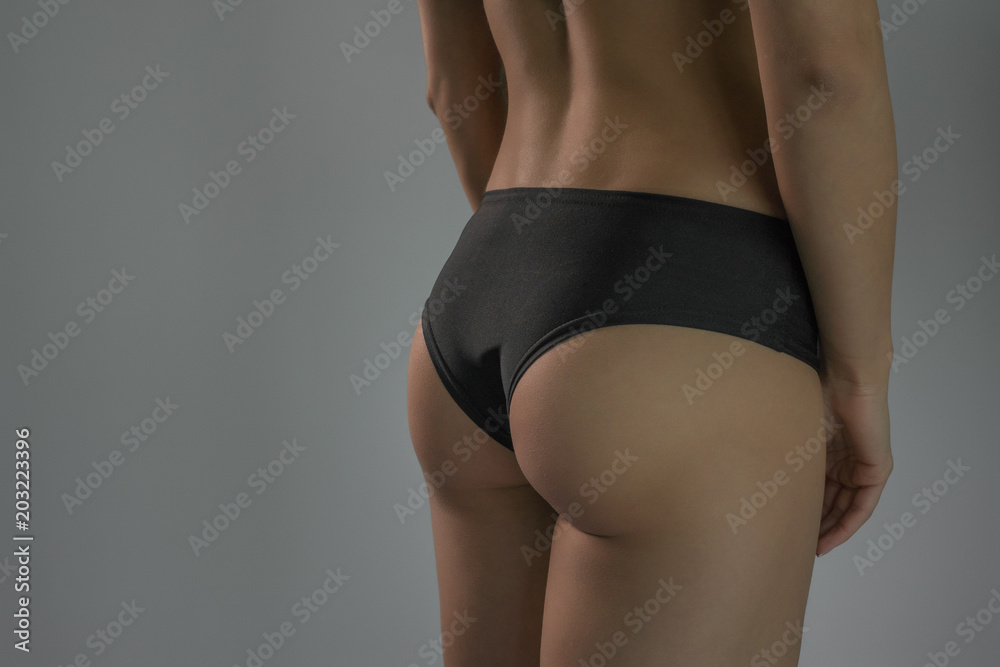 Fototapeta premium A sporty ass girl on a gray background. Sports figure