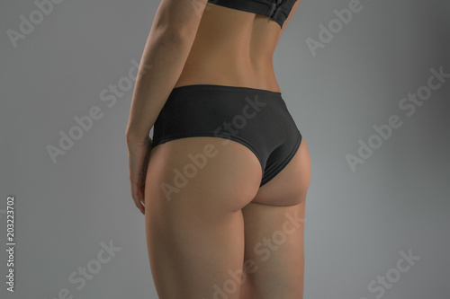 A sporty ass girl on a gray background. Sports figure
