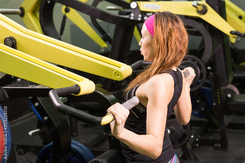 woman at the gym exercising on a machine. woman at the gym exercising on a machine.