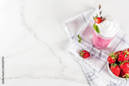Cold strawberry  milkshake with fresh berries and mint on white marble background copy space top view
